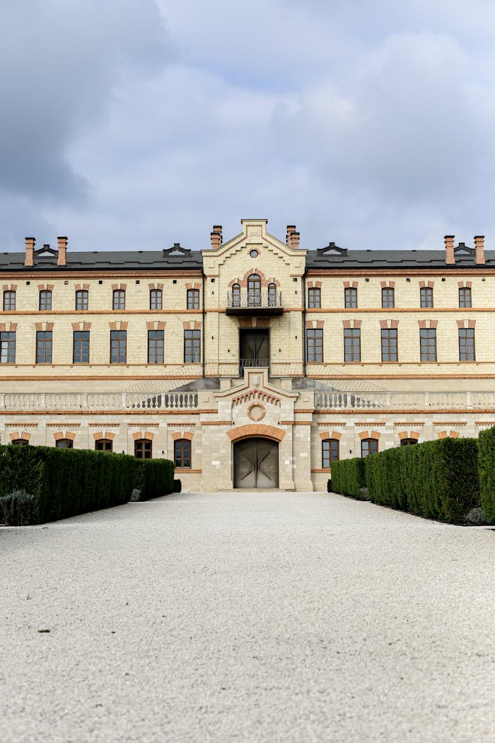 Elegant facade of a historic mansion with a symmetrical design and landscaped hedges.